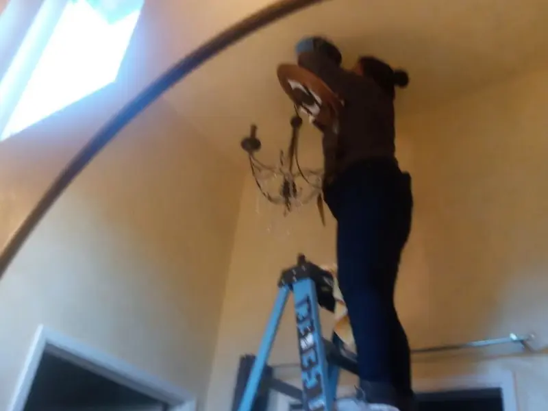 Electrician installing a chandelier in a Heathrow residence